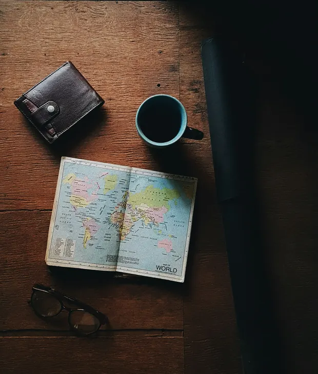 Desk with a world atlas, a coffee cup and a wallet