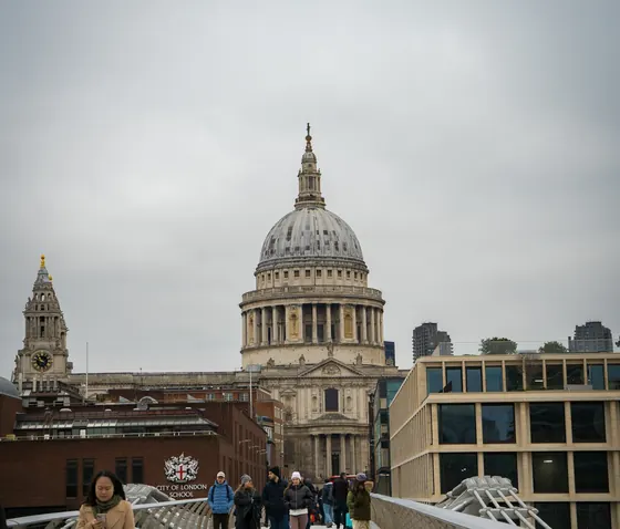 Pedestrians crossing a bridge in London with St Paul's Cathedral ahead